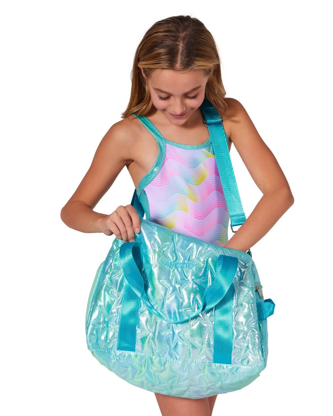 Girl holding a large shiny turquoise bag with a shoulder strap on.