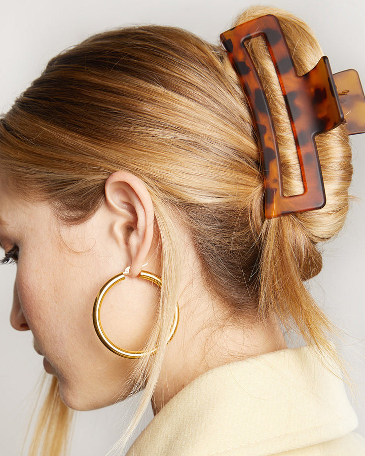 Person with tortoiseshell hair clip holding bunched up hair.
