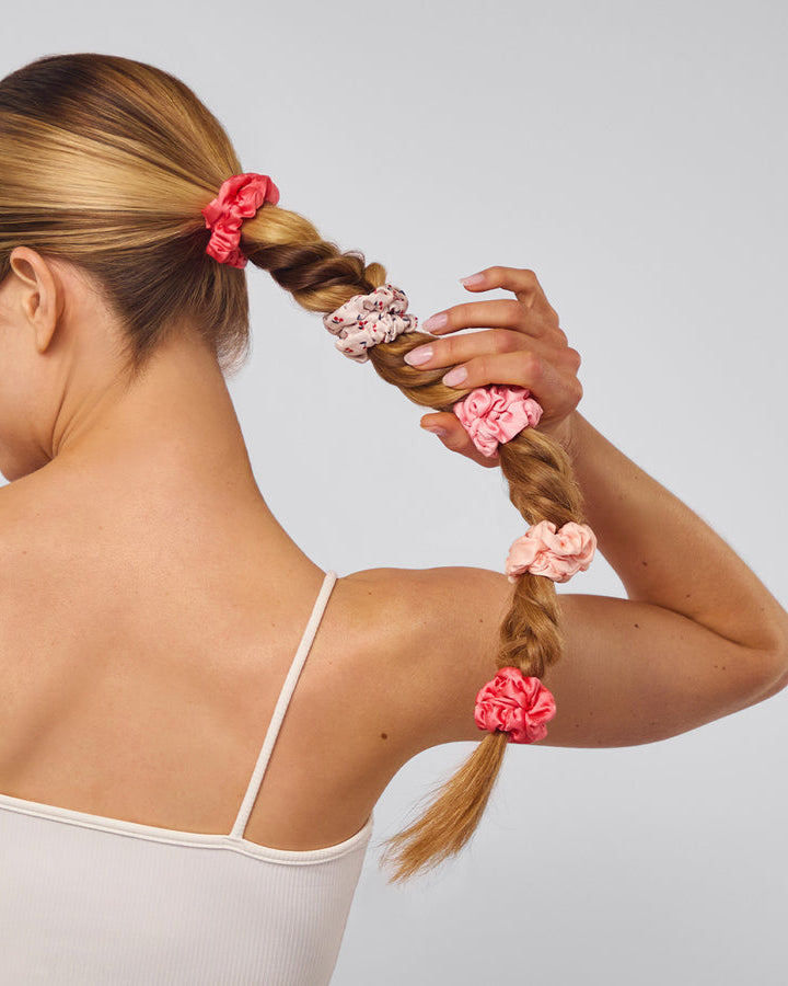 Woman with braided hair adorned with pink scrunchies.