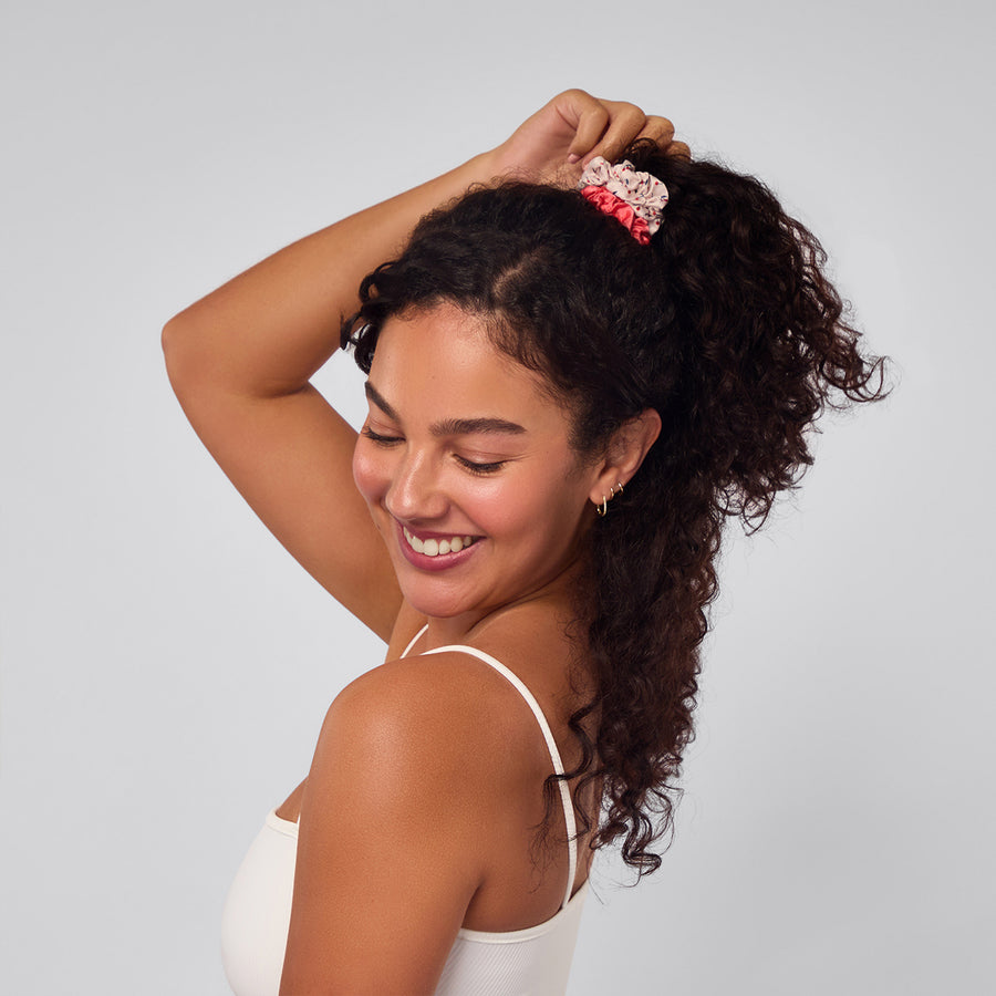 Woman with thick curly ponytail tied up with scrunchies.
