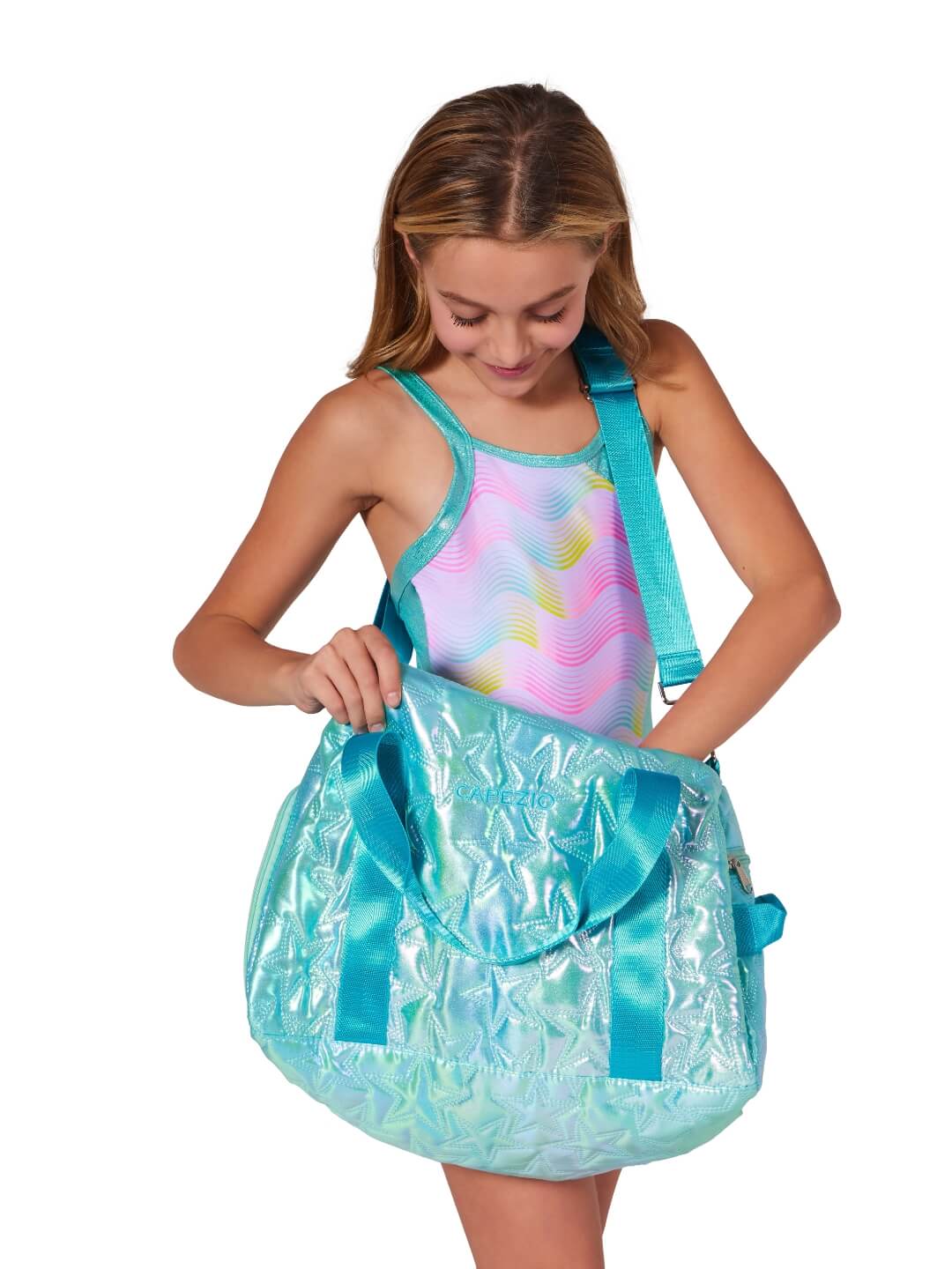 Girl holding a large shiny turquoise bag with a shoulder strap on.