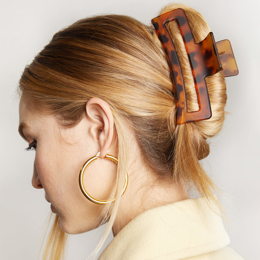 Person with tortoiseshell hair clip holding bunched up hair.