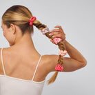 Woman with braided hair adorned with pink scrunchies.